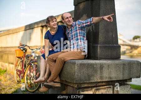 Heureux jeune famille. Couple amoureux assis sur la bordure du talus et parler avec passion. Banque D'Images