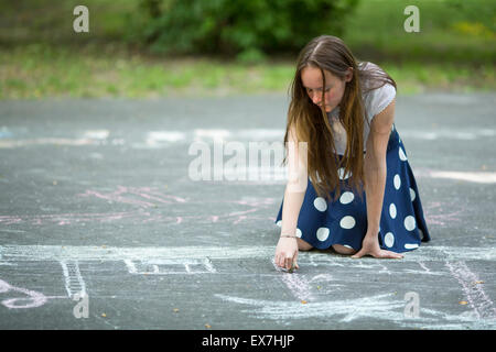 Jolie teen girl attire avec de la craie sur le trottoir. Banque D'Images