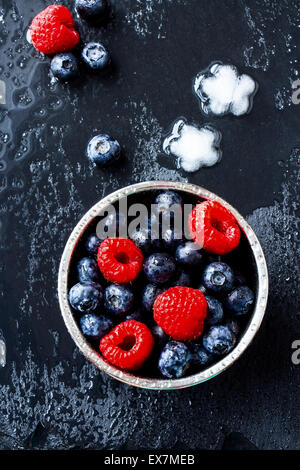 Vue de dessus de mélanger dans un bol de fruits et de la glace sur fond gris foncé. Banque D'Images