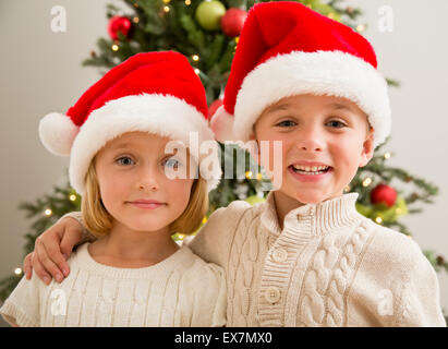 Frère et soeur (6-7) (6-7) wearing Santa hats Banque D'Images