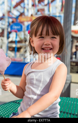 Trois ans girl eating Cotton Candy au parc d'attractions, San Diego, Californie Banque D'Images