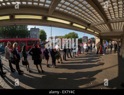 Morden, London UK. 9e juillet 2015. Tôt le matin, les navetteurs en attente soleil pour les autobus au centre de Londres de l'extérieur de Morden parvis de la gare. Morden, terminus sud de la ligne du Nord, normalement dessert la ville et le West End. Credit : Malcolm Park editorial/Alamy Live News Banque D'Images