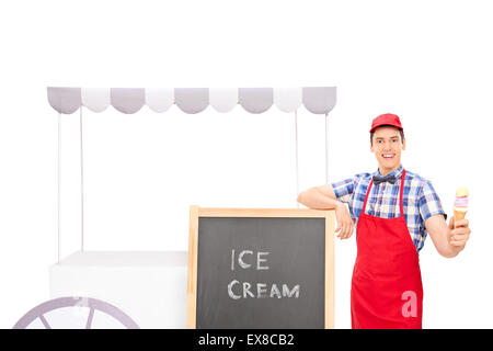 Jeune homme debout du vendeur par un stand de crème glacée et de la tenue d'un cornet de crème glacée isolé sur fond blanc Banque D'Images