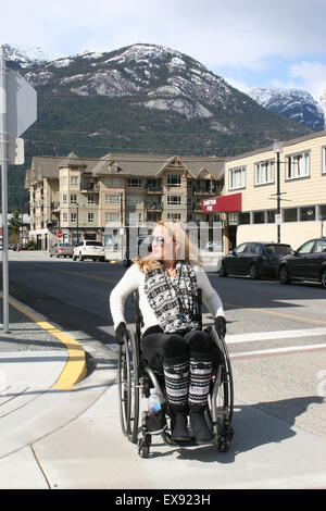 Femme à l'aide d'un fauteuil roulant dans un village alpin canadien Banque D'Images