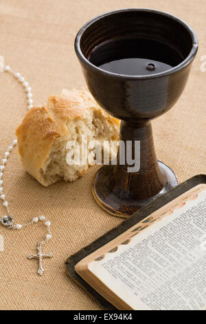 La Sainte Bible, chapelet de perles, morceau de pain et calice avec du vin Banque D'Images