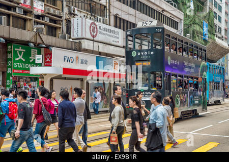 Les banlieusards crossing busy street, hong kong avec un tram à l'arrière-plan Banque D'Images