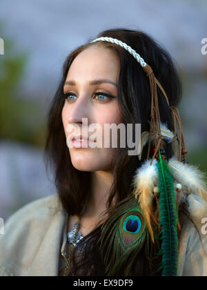 Belle jeune femme portant un casque en plumes, soir d'été Banque D'Images