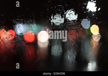 Lumières floues à travers une fenêtre des pluies, créant un effet bokeh Banque D'Images