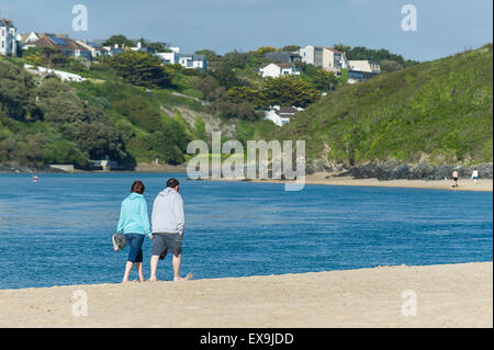 Un couple en train de marcher le long des berges de la rivière plage de Crantock sur Gannel à Newquay, Cornwall. Banque D'Images