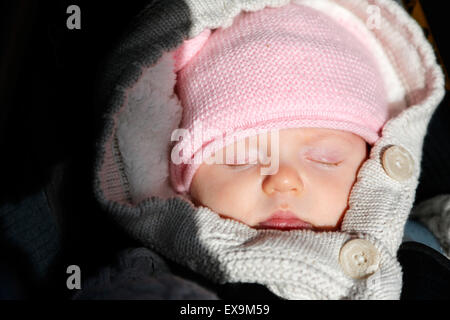 Un bébé enveloppé dans des vêtements d'hiver chauds, douillet et chaleureux endormi dans sa poussette malgré le froid hiver anglais Banque D'Images