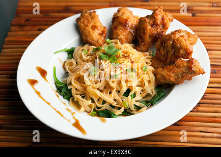 Ailes de poulet avec des nouilles et épinards Banque D'Images