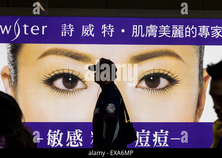 En Asie, Taiwan, Taipei, Silhouette d'homme marchant passé allumé billboard de Chinese woman's eyes inside système de métro MTR de Taipei Banque D'Images