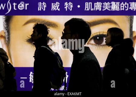 En Asie, Taiwan, Taipei, Silhouette de passagers en passant devant des panneaux lumineux de la femme chinoise de Taipei à l'intérieur des yeux Temi MTR Banque D'Images