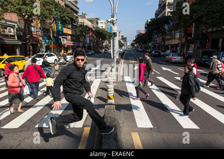 En Asie, Taiwan, Taipei, jeune homme bondit sur le passé la barrière de marcher à travers la foule près de concordance marché Dongmen sur sunny winte Banque D'Images