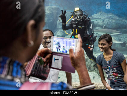 En Asie, Singapour, les touristes posent pour les instantanés en face de scuba diver en natation à l'intérieur du réservoir requin massif S.E.A. Aquarium Banque D'Images