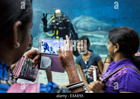 En Asie, Singapour, les touristes posent pour les instantanés en face de scuba diver en natation à l'intérieur du réservoir requin massif S.E.A. Aquarium Banque D'Images