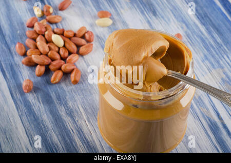 Le beurre d'arachide en pot sur fond bleu. Shallow dof. Banque D'Images