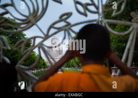 Un moine faisant attention à une statue de 64 pieds de haut du Grand Bouddha derrière la clôture à Bodh Gaya, Bihar, Inde. Banque D'Images