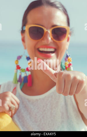 Portrait of a young woman showing a Thumbs up sign. Belle jeune femme de donner un coup de pouce tandis qu'à la plage. L'accent sur le pouce Banque D'Images