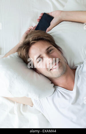Man relaxing on bed, portrait Banque D'Images