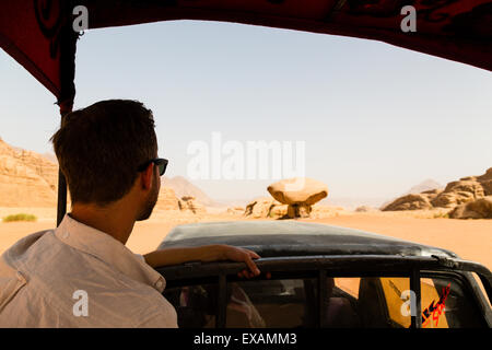 Wadi Rum, Jordanie. Au cours d'un tourisme européen mâle jeep safari Champignons approche Rock dans le désert. Banque D'Images