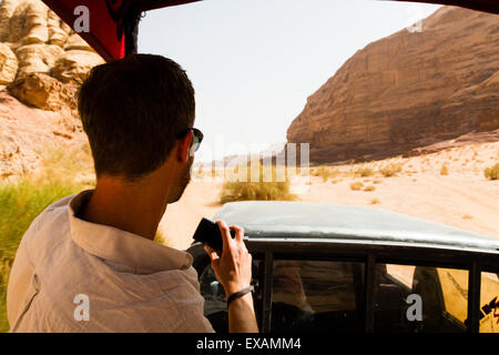 Wadi Rum, Jordanie. Tenir l'appareil photo de touriste européen mâle au cours d'un safari en jeep dans le désert. Banque D'Images