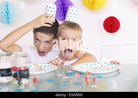 Jeunes Frères making faces lors d'un anniversaire Banque D'Images