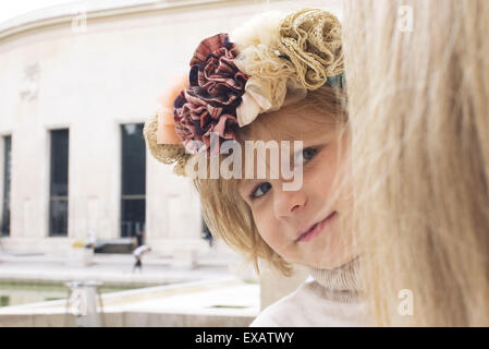 Little girl peeking autour de mother's head, portrait Banque D'Images