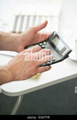Man's hands holding calculator Banque D'Images