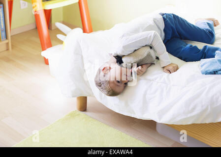 Boy lying on bed with stuffed toy Banque D'Images