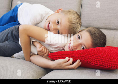 Jeunes Frères lying together on sofa Banque D'Images