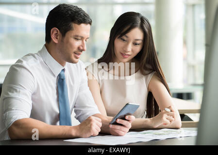 Collègues looking at smartphone together in office Banque D'Images