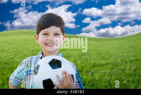 Cute Smiling Young Boy Holding Soccer Ball sur l'herbe verte dans le parc. Banque D'Images