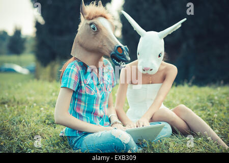 Cheval masque lapin et soeurs des femmes à l'aide d'amis smartphone ou tablette dans le parc Banque D'Images