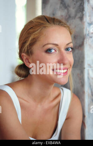 Close up portrait of an attractive young blonde woman smiling avec éclairage naturel Banque D'Images