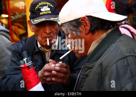 La Paz, Bolivie, 10 juillet 2015. Les manifestants de Potosi fument des cigarettes et utilisent du papier de soie dans leurs narines pour lutter contre les effets des gaz lacrymogènes lors d'une manifestation organisée par le Comité civique de Potosi et ses partisans. Ils sont à la Paz pour exiger que le gouvernement tienne les promesses électorales faites à la région dans le passé. La police a utilisé des gaz lacrymogènes pour empêcher les manifestants d'entrer sur la Plaza Murillo crédit : James Brunker / Alamy Live News Banque D'Images