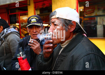 La Paz, Bolivie, 10 juillet 2015. Les manifestants de Potosi fument des cigarettes et utilisent du papier de soie dans leurs narines pour lutter contre les effets des gaz lacrymogènes lors d'une manifestation organisée par le Comité civique de Potosi et ses partisans. Ils sont à la Paz pour exiger que le gouvernement tienne les promesses électorales faites à la région dans le passé, qui comprennent la construction d'une cimenterie, d'hôpitaux, d'une centrale hydroélectrique et d'un aéroport international. La police a utilisé des gaz lacrymogènes pour empêcher les manifestants d'entrer sur la Plaza Murillo crédit : James Brunker / Alamy Live News Banque D'Images