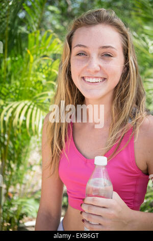 Jeune fille riant tout en tenant une bouteille d'eau. Une adolescente, 13 ans, Nayarit, Mexique Banque D'Images