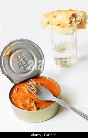 Le sprat en conserve à la sauce tomate, un tablier en aluminium et un verre de vodka à facettes Banque D'Images