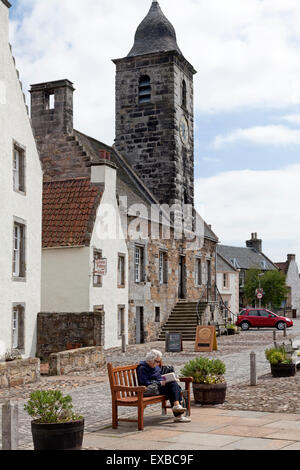 Femme âgée lisant sur un banc en ville House Square, Culross, Fife Banque D'Images