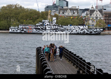 Les touristes sur l'Oxo Tower Pier avec HMS Président couverts dans la PREMIÈRE GUERRE MONDIALE, dazzle camouflage sur la Tamise, Londres, Angleterre, Royaume-Uni. Banque D'Images