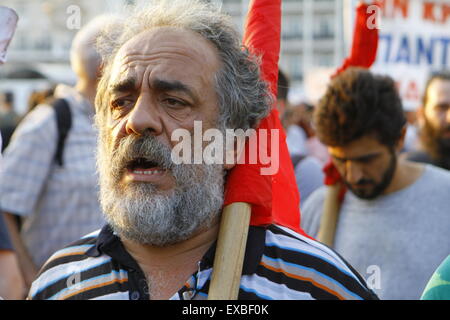 Athènes, Grèce. 10 juillet 2015. Un manifestant porte un drapeau rouge enroulé par-dessus son épaule à la manifestation anti-austérité à Athènes. Les membres du syndicat communiste PAME se sont rassemblées devant le parlement grec. Ils ont demandé que le gouvernement, en l'honneur de la suite de l'organisation d'un référendum et de ne pas proposer de nouvelles mesures d'austérité comme exigence d'un renflouement de la Troïka. Cette manifestation a eu lieu alors que le Parlement grec a débattu des nouvelles mesures d'austérité. Crédit : Michael Debets/Alamy Live News Banque D'Images