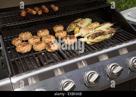 La cuisson des aliments sur un barbecue à gaz. Saucisses, hamburgers de dinde et de maïs prêt à manger Banque D'Images