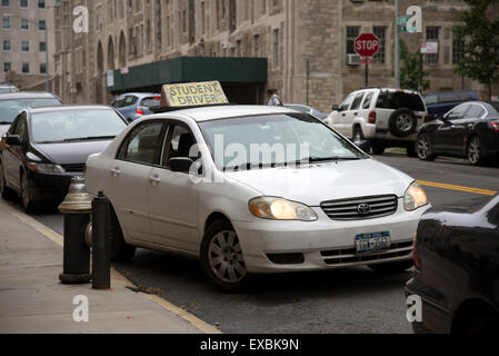 Pilote d'étudiant d'apprendre à conduire dans une rue de New York USA renverser dans un espace entre les voitures en stationnement Banque D'Images