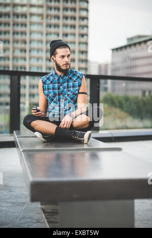 Handsome young man using smartphone hipster barbu et écouter la musique avec vos écouteurs dans la ville Banque D'Images
