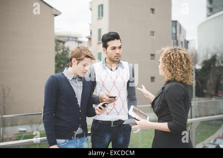 Les gens d'affaires de plein air travail multiraciale en ville connecté avec des dispositifs technologiques Banque D'Images