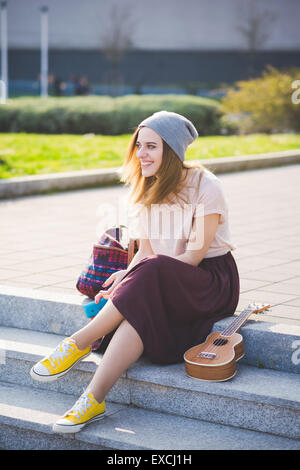 Belle blonde jeune femme dans la ville hipster avec ukulele Banque D'Images