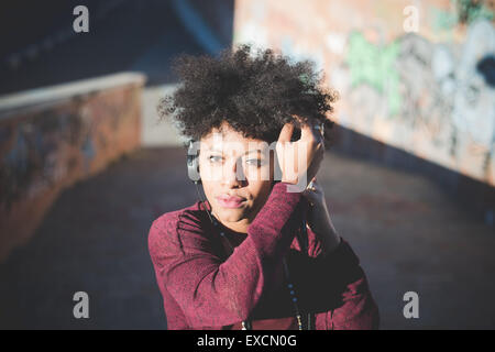 De beaux cheveux noirs frisés femme africaine à écouter de la musique avec des écouteurs en ville Banque D'Images