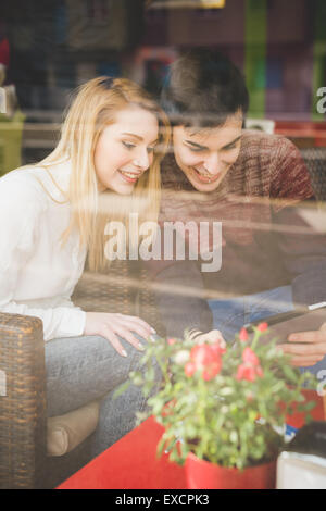 Les jeunes amateurs de beau couple assis au bar à l'aide de tablette sans fil connecté en ligne Banque D'Images