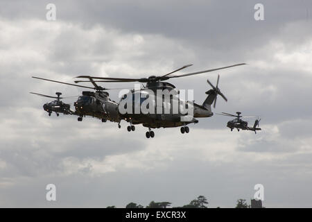 Yeovilton, Somerset, Royaume-Uni. 11 juillet, 2015. L'une des nouvelles armes de l'air flotte Merlin H C Mk 3 conduit un Sea King H C Mk 4 en vol à la Journée de l'Air International Yeovilton, flanqué d'une paire d'hélicoptères d'attaque Apache utilisé par l'Army Air Corps, le Merlin a totalement remplacé le Sea King dans la Force d'hélicoptères de commando en mars 2016 Crédit : David Billinge/Alamy Live News Banque D'Images